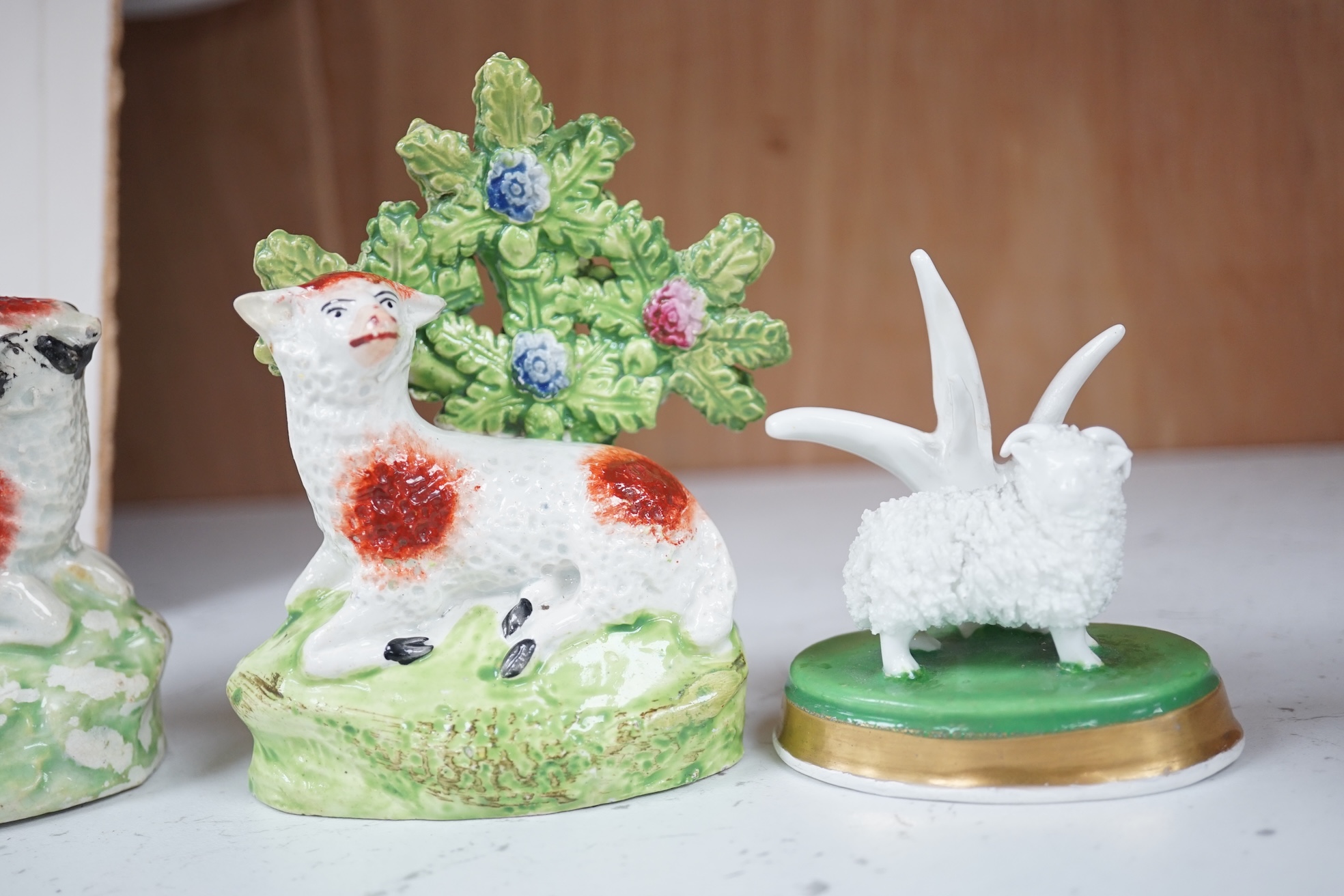 A pair of early 19th century pearlware models of sheep, an English porcelain ‘sheep’ ring tree and a Derby figure of a cherub, tallest 10 cm. Condition - ring tree restored the others fair to good